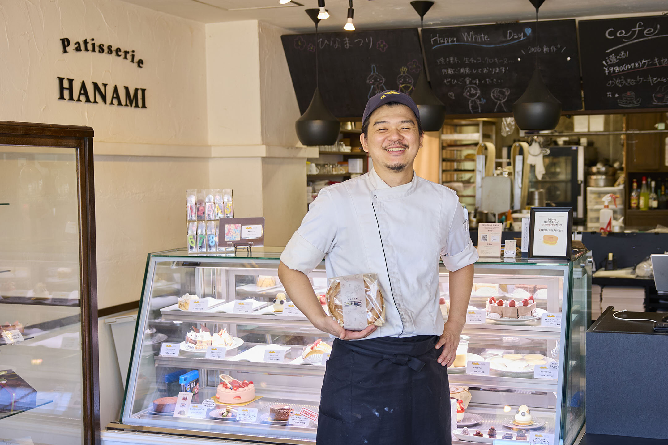 シフォンケーキを片手に携え、笑顔の店主・林さん