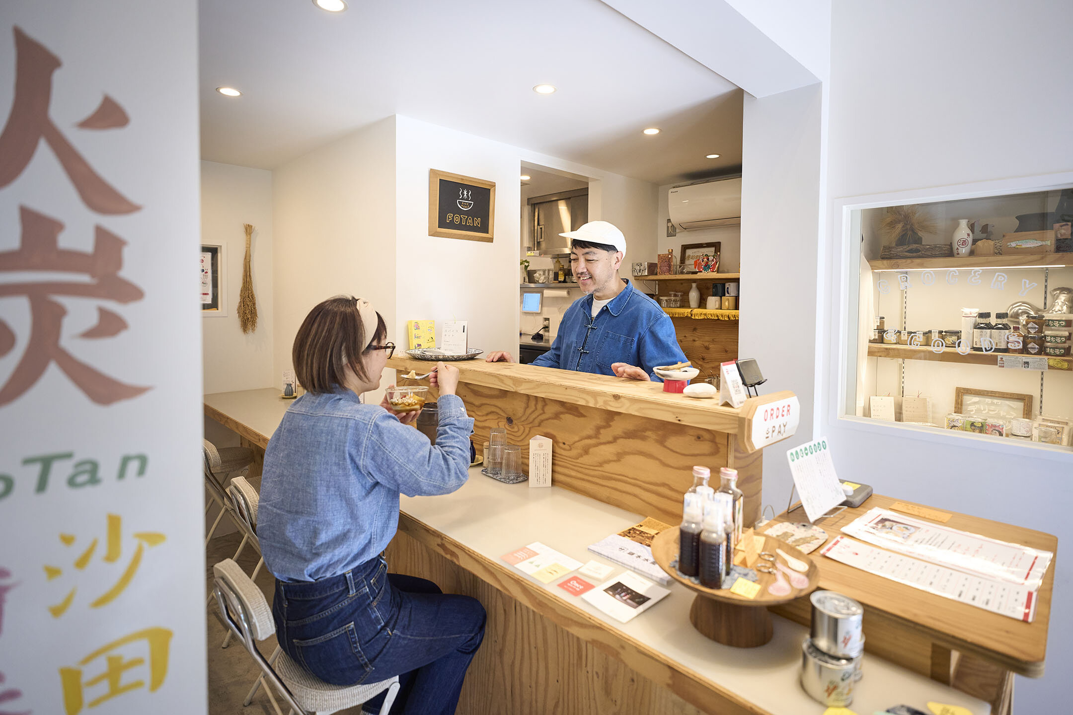 『Rice meals FoTan』の店内、カウンター越しに常連さんと談笑する堀田さん
