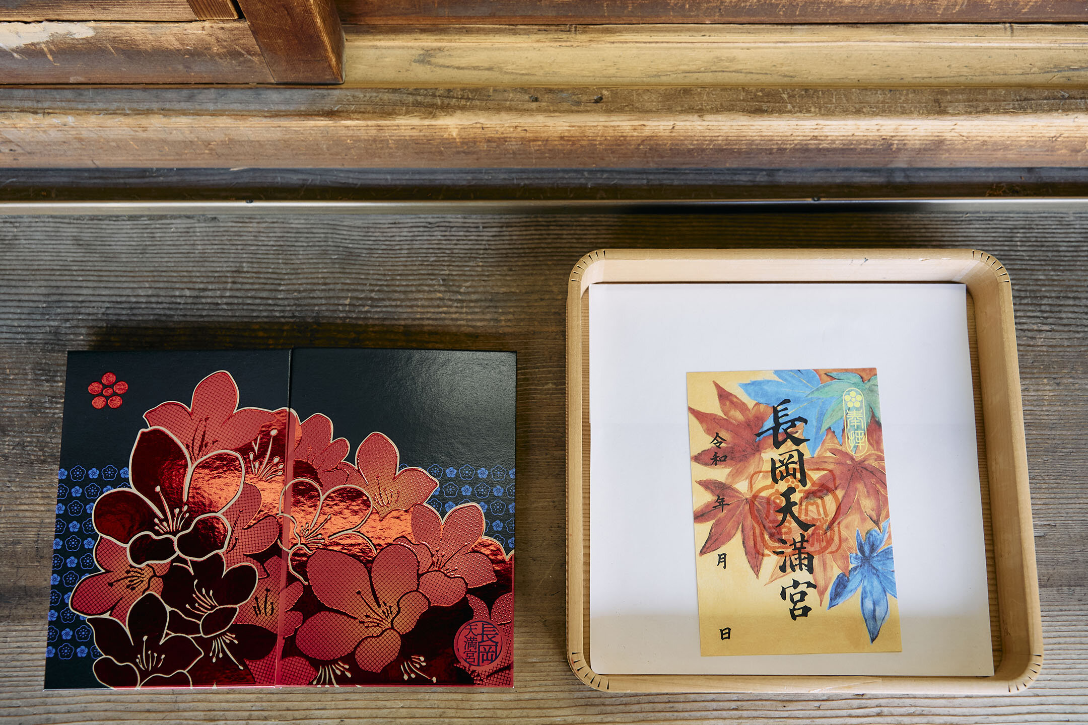 左はきりしまつつじを赤メタリックの箔であしらった「御朱印帳」。右は日本画家の丸山勉さんによる「紅葉」をテーマに描いた「いろどり御朱印」