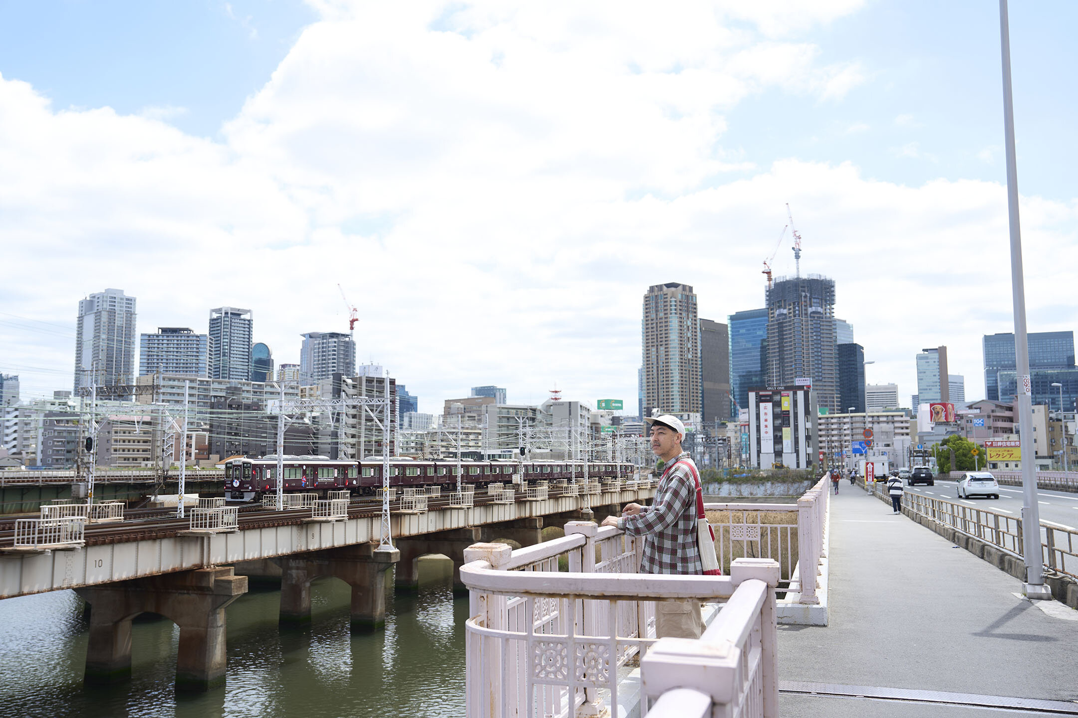 阪急電車が見られる橋の上、中津界隈の景色を楽しむ堀田さん