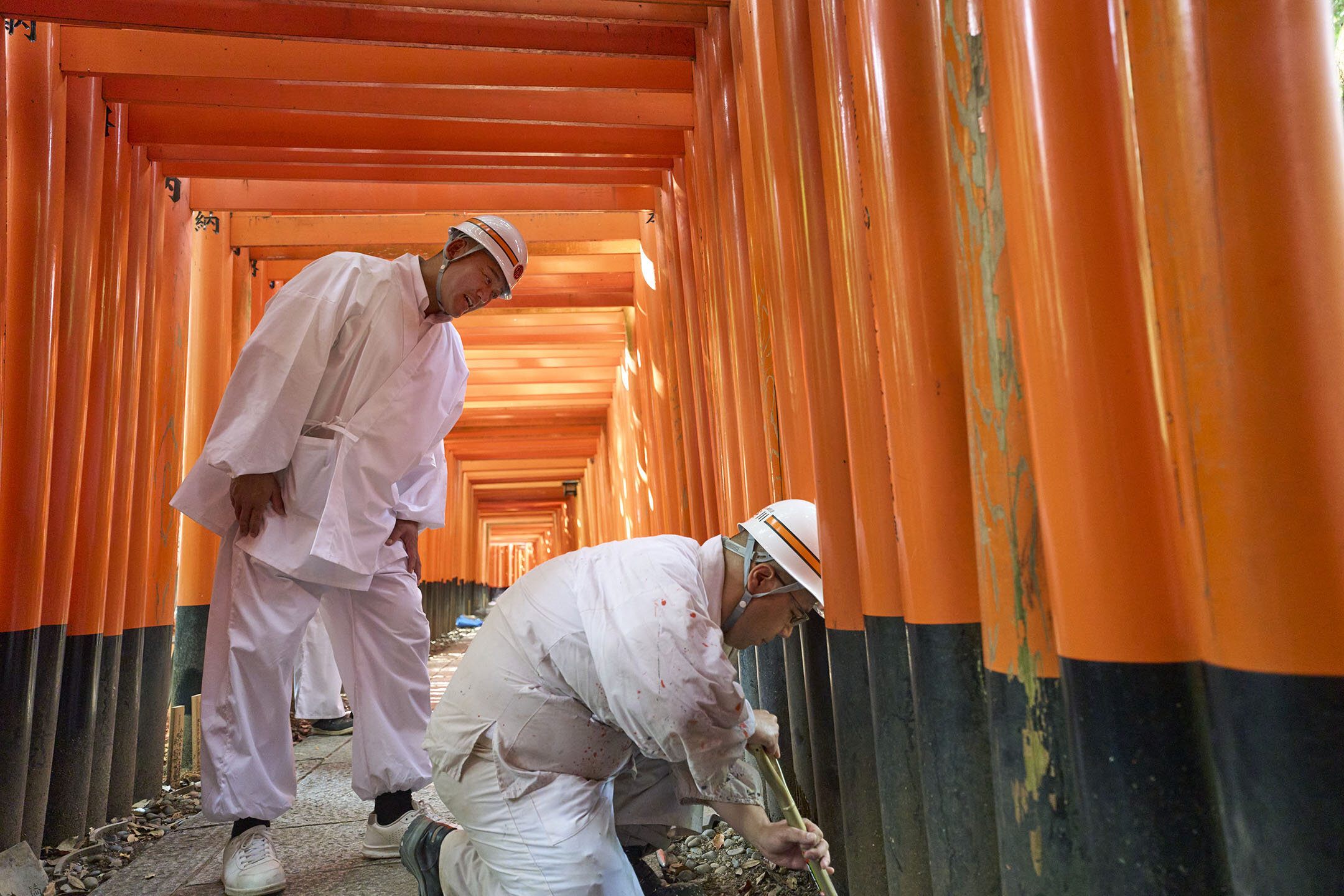 鳥居を建てるための穴を掘る職人さんと、見守る長谷川さん