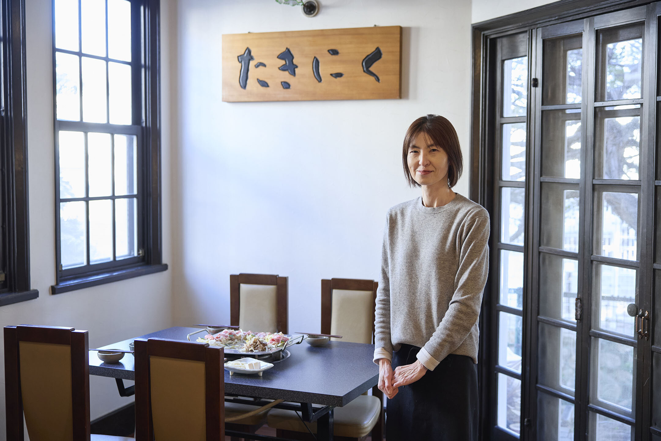 テーブルのそばでにこやかに立つ、店主の永田久美子さん。
