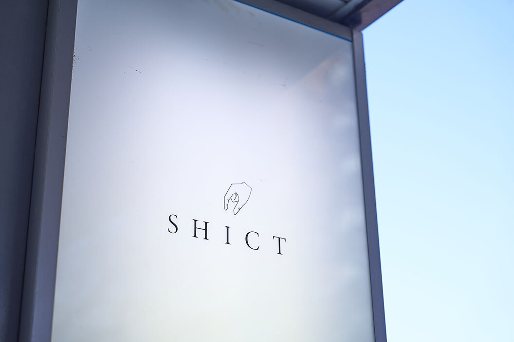 『シクト』の看板、指先のイラストが描かれたロゴが特徴的