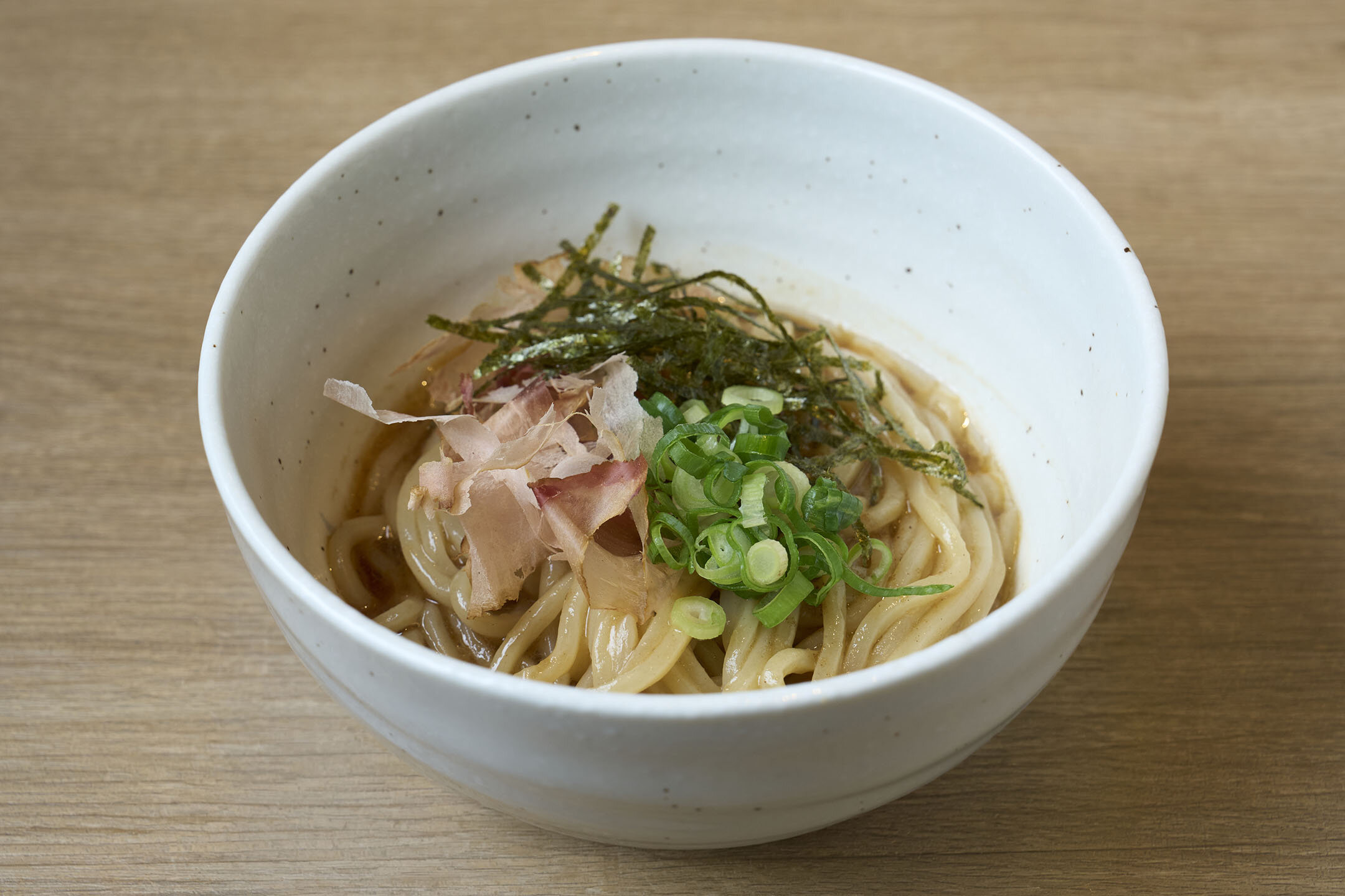 茶碗ほどの器に入った「二杯目そば」の油そば。かつおぶしや刻みのり、青ネギがトッピングされている。