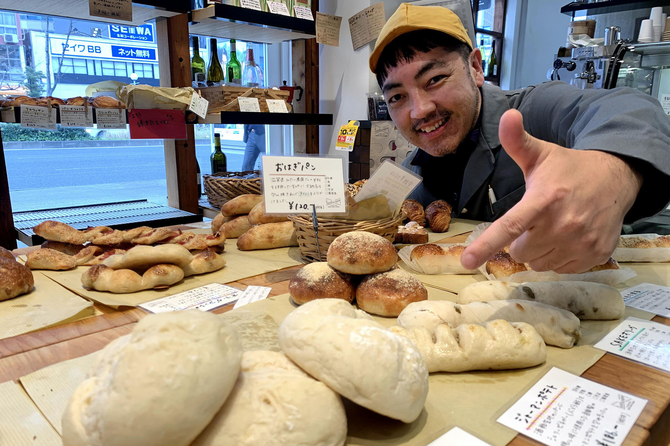 『foodscape! Bakery』の店内、自慢のパンを笑顔で指さす堀田さん