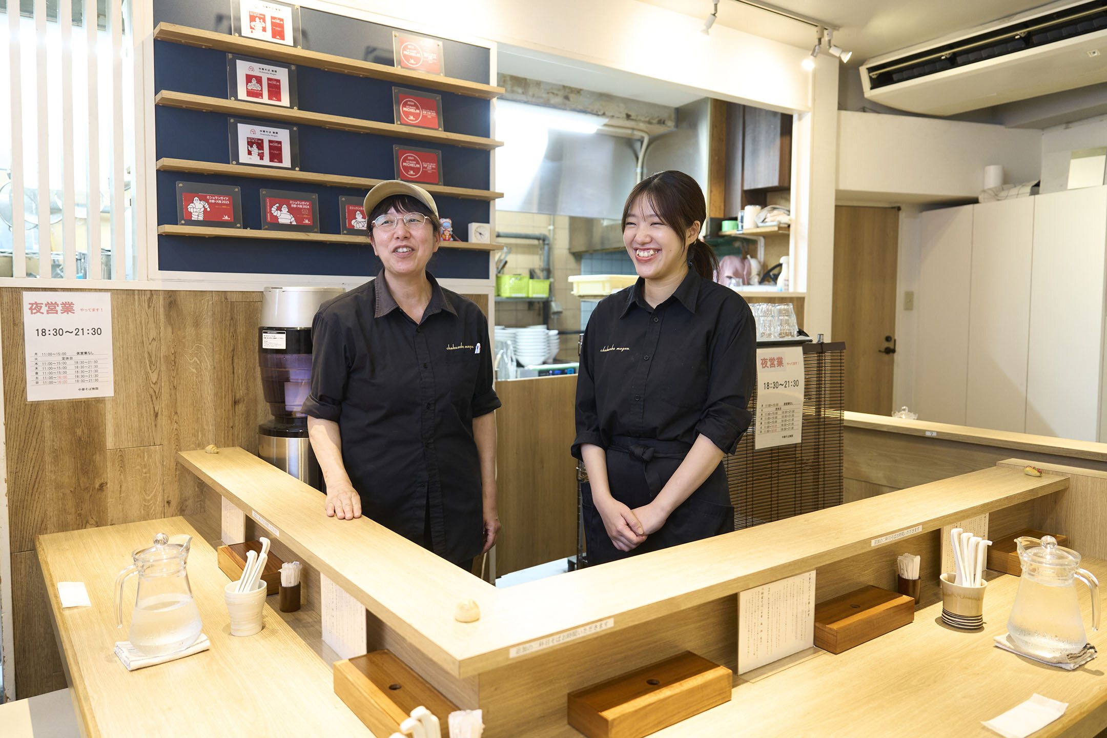 カウンター内で笑顔で話す、店長の岡田良枝さん（右）と、女将の晴枝さん（左）