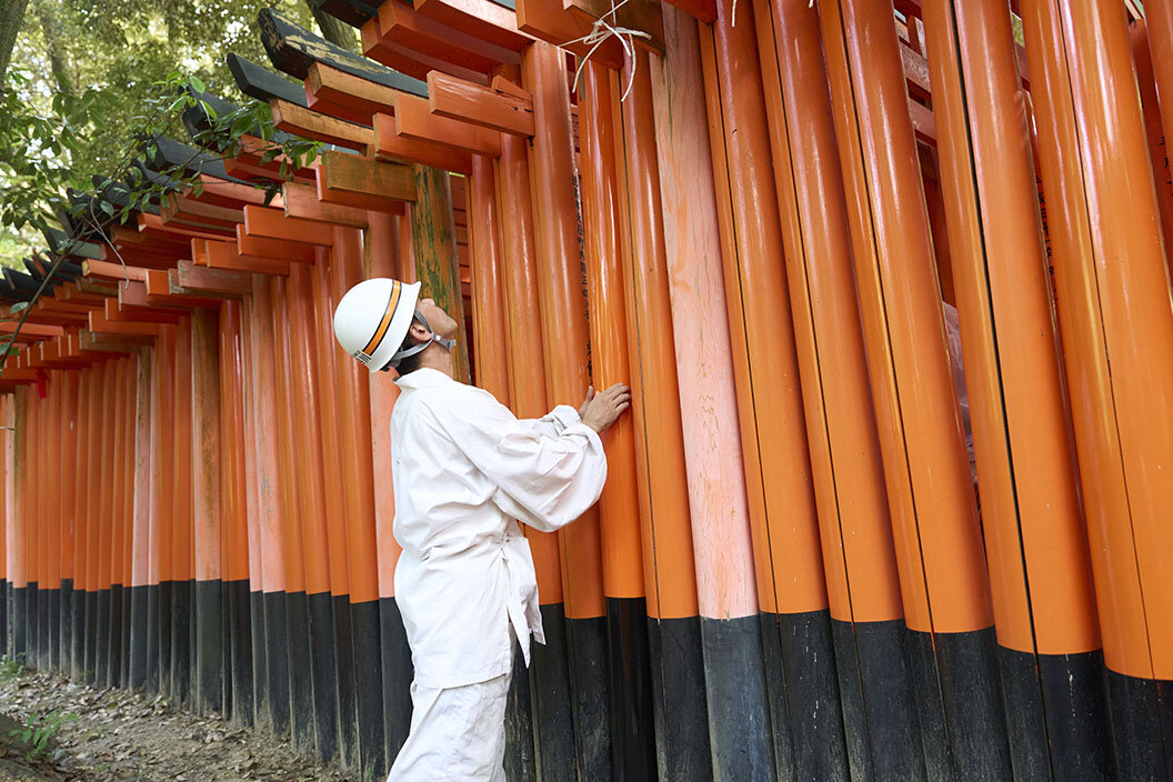 鳥居の外側から柱のバランスを調整する職人さん