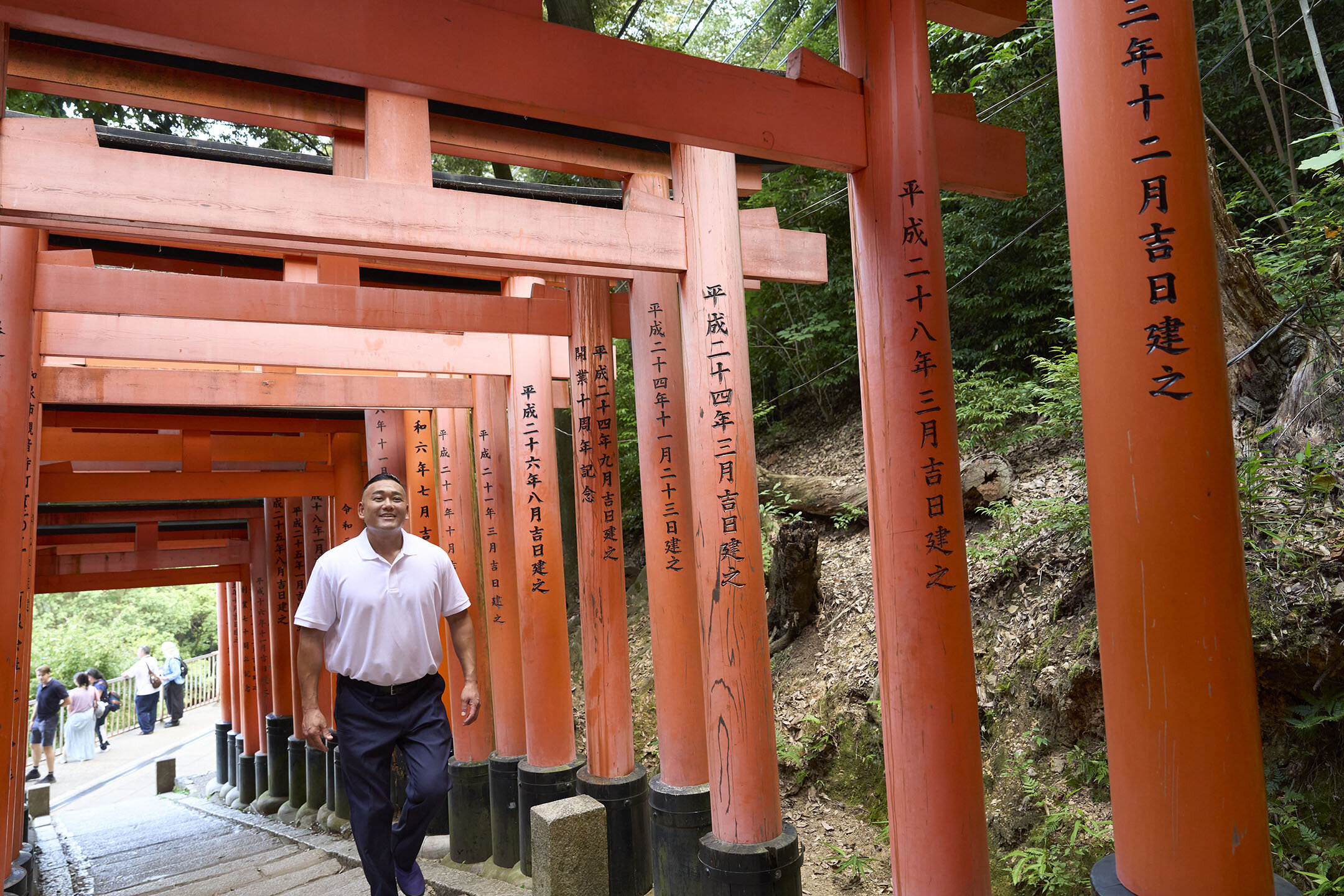 鳥居が建つ稲荷山の石段を軽やかに登る長谷川さん