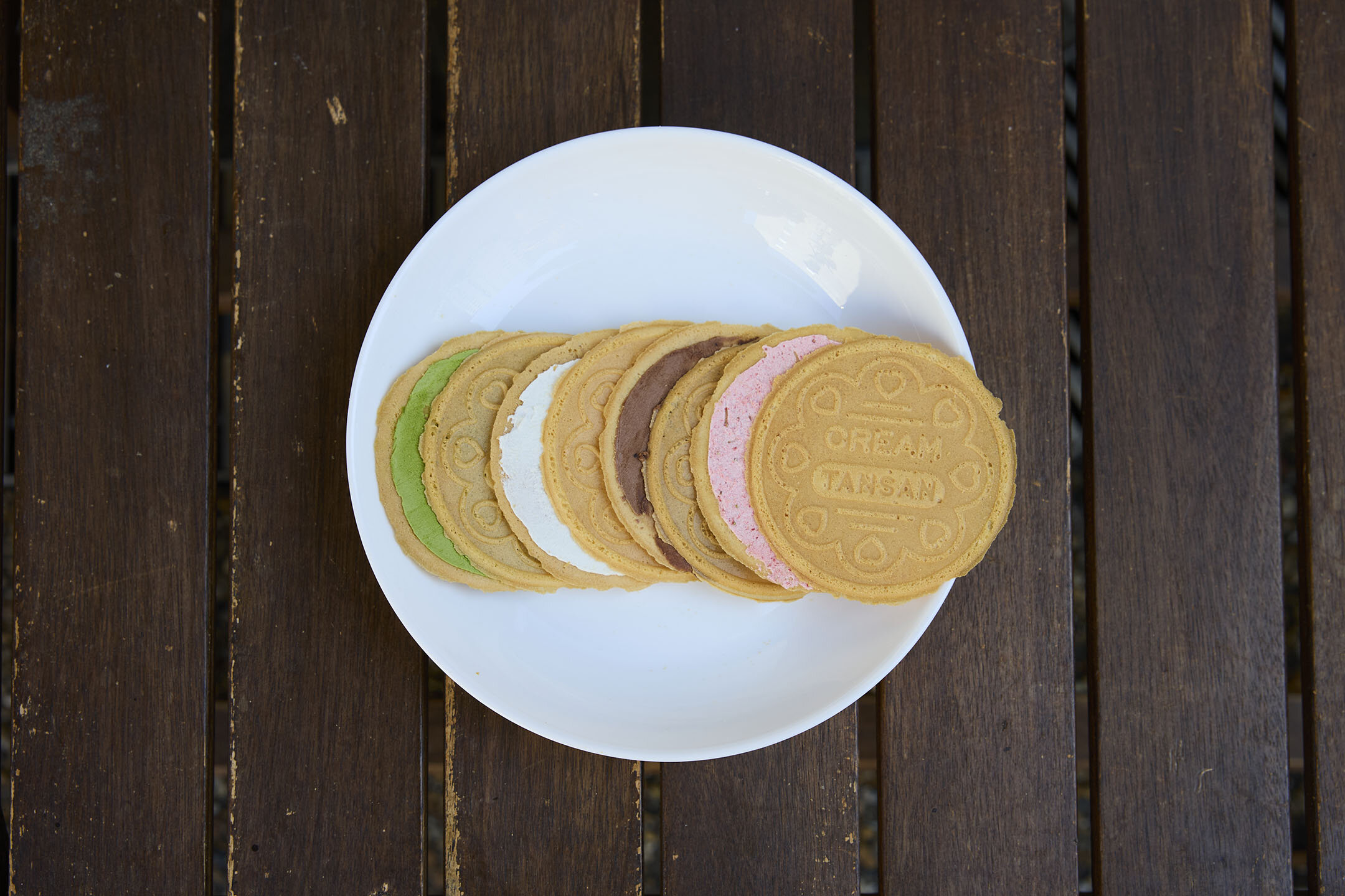 左から、緑は抹茶、白はレモン、茶色はチョコレート、ピンクはストロベリーの順で、クリーム炭酸せんべいのクリームが見えている様子