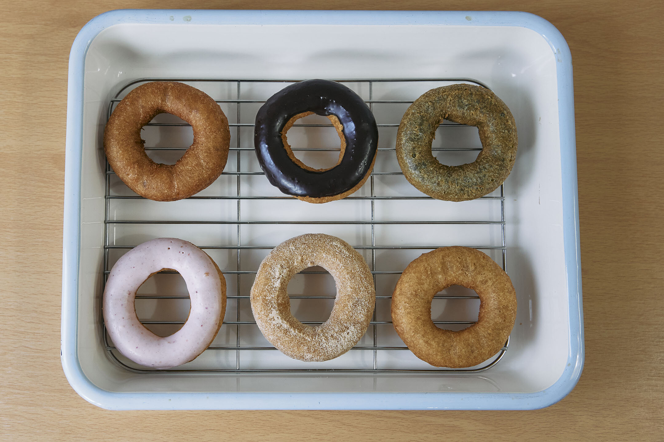 バットの上に6つのドーナツが並ぶ。緑色をしたまっちゃ味やピンク色のイチゴがけ味など見た目もさまざま