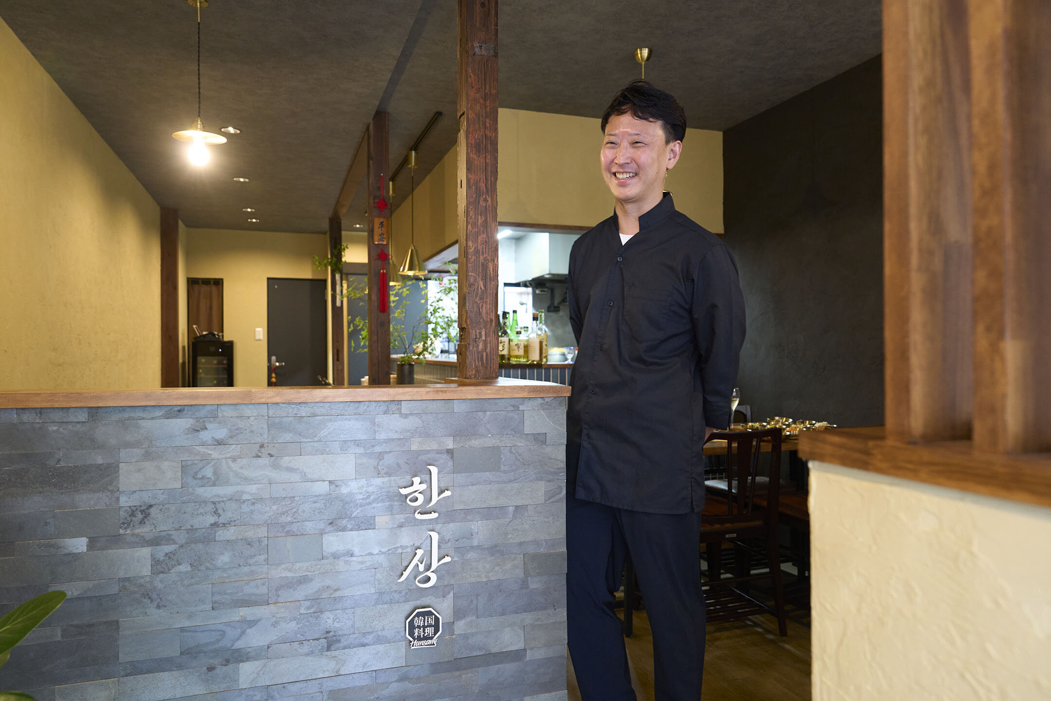 店内入口で、笑顔で語るオーナーシェフ。