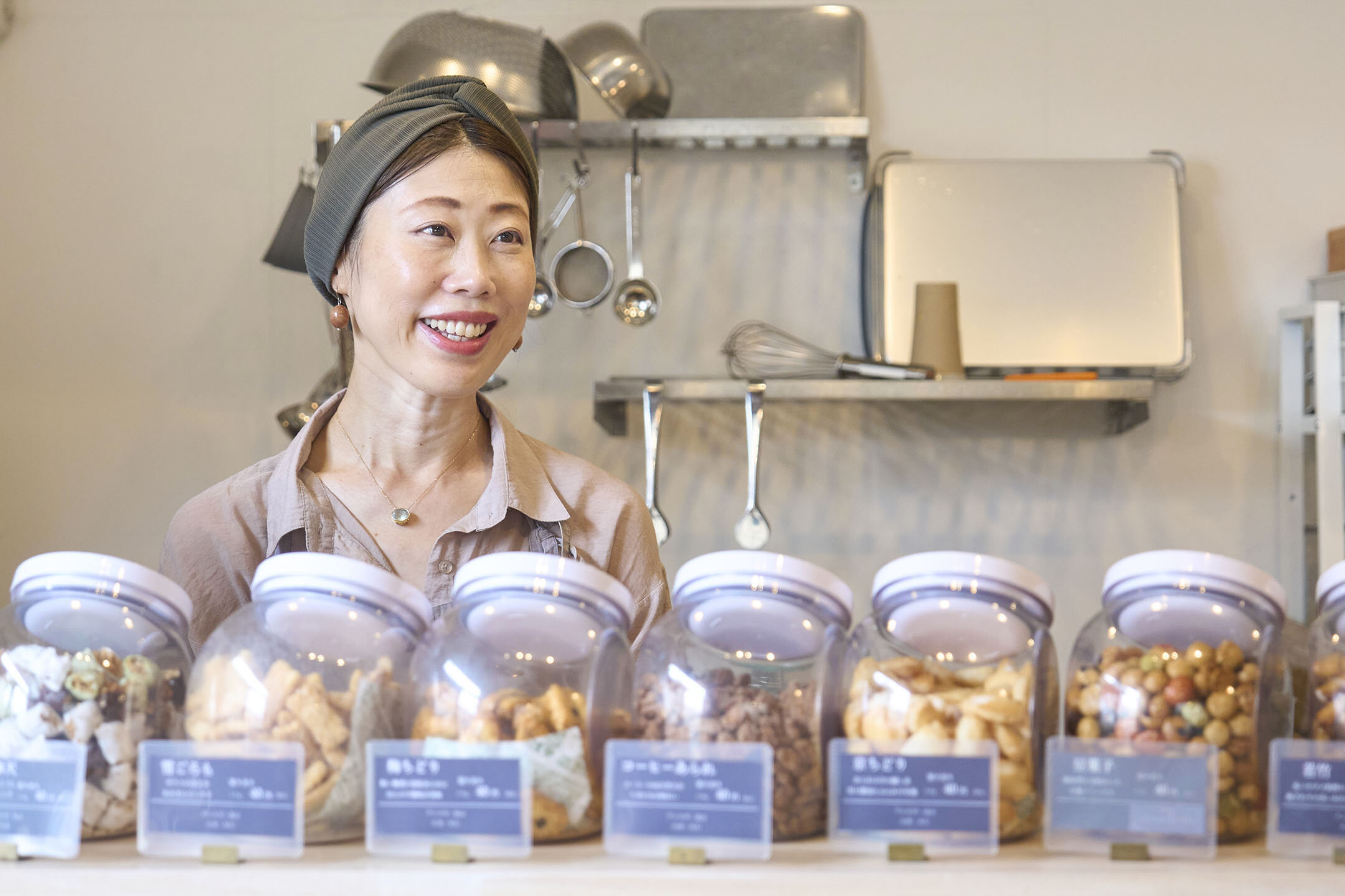 ずらりと並んだおかきボックスの奥で話す由紀子さん