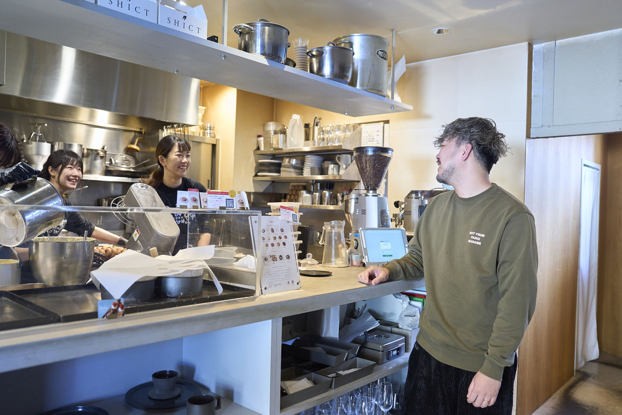 『シクト』の厨房前、女性スタッフと談笑する寺地さん