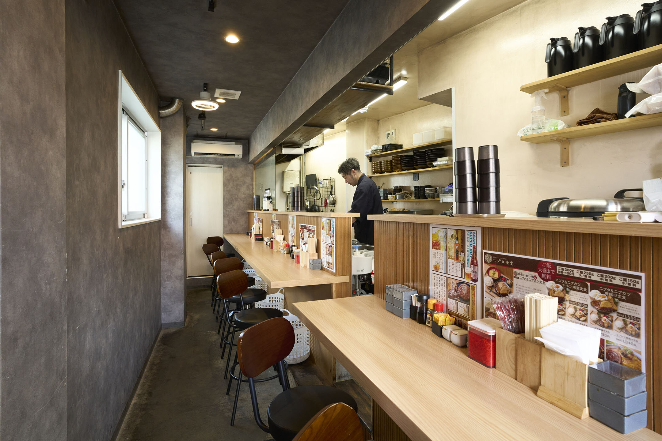 カウンターのみの店内。奥のカウンター内で店長が作業をしている様子。